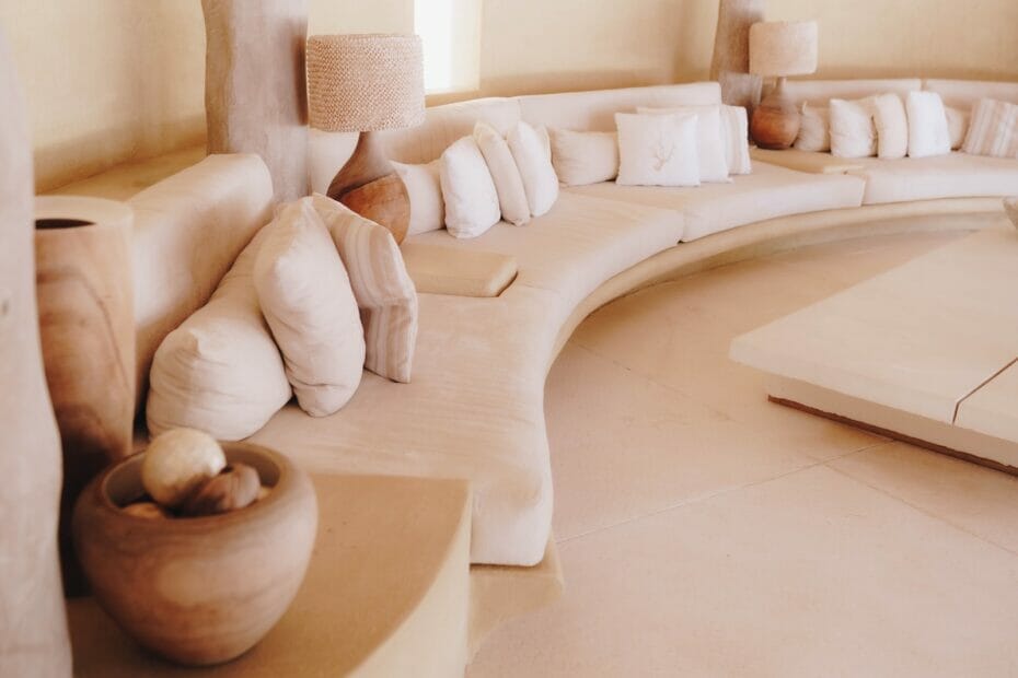 a curved couch sitting in a living room next to a lamp