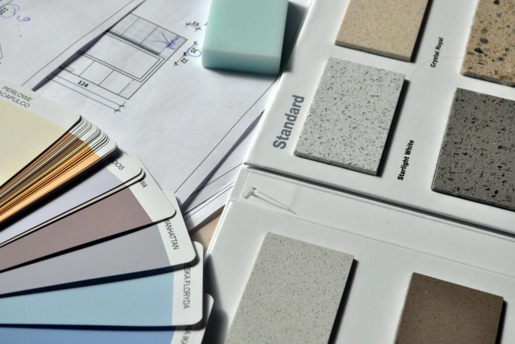 Una colección de muestras de pintura muestras de azulejos y un borrador sobre un plano arquitectónico perfecto para guiarlo en la remodelación de la cocina y evitar errores comunes-8 Errores comunes en la remodelación de cocinas (¡y Cómo Evitarlos!)