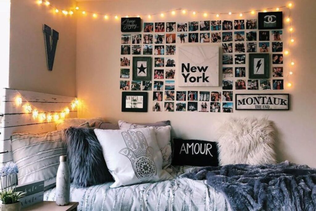 Dormitorio acogedor con guirnaldas de luces un collage de fotos en la pared y una cama adornada con almohadas mullidas y una manta La decoración incluye un cartel de Nueva York y una botella en la mesa auxiliar perfecto para quienes buscan transformar su hogar en la casa ideal después de los-Lo que no debes tener en tu casa despues de los 30: es hora de transformar tu hogar